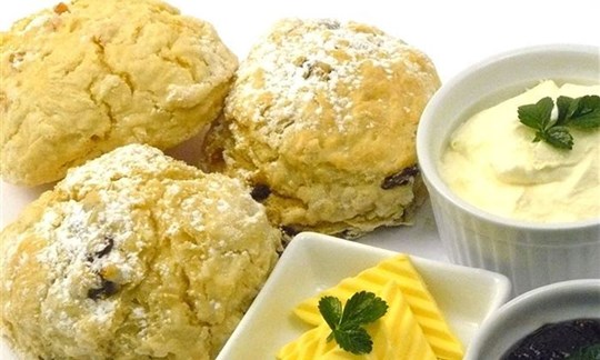 Scones with freshly whipped cream, butter, jam and utensils.(v)